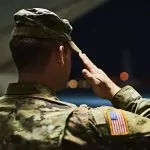 Officer saluting inside a hanger facing the outdoors at night; prevent adverse information in promotion file