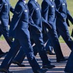 Image shows Air Force basic training graduation parade, new airmen in their dress blues marching in step; USAF discharge rules for sexual offenders; discharge policy sexual offenders